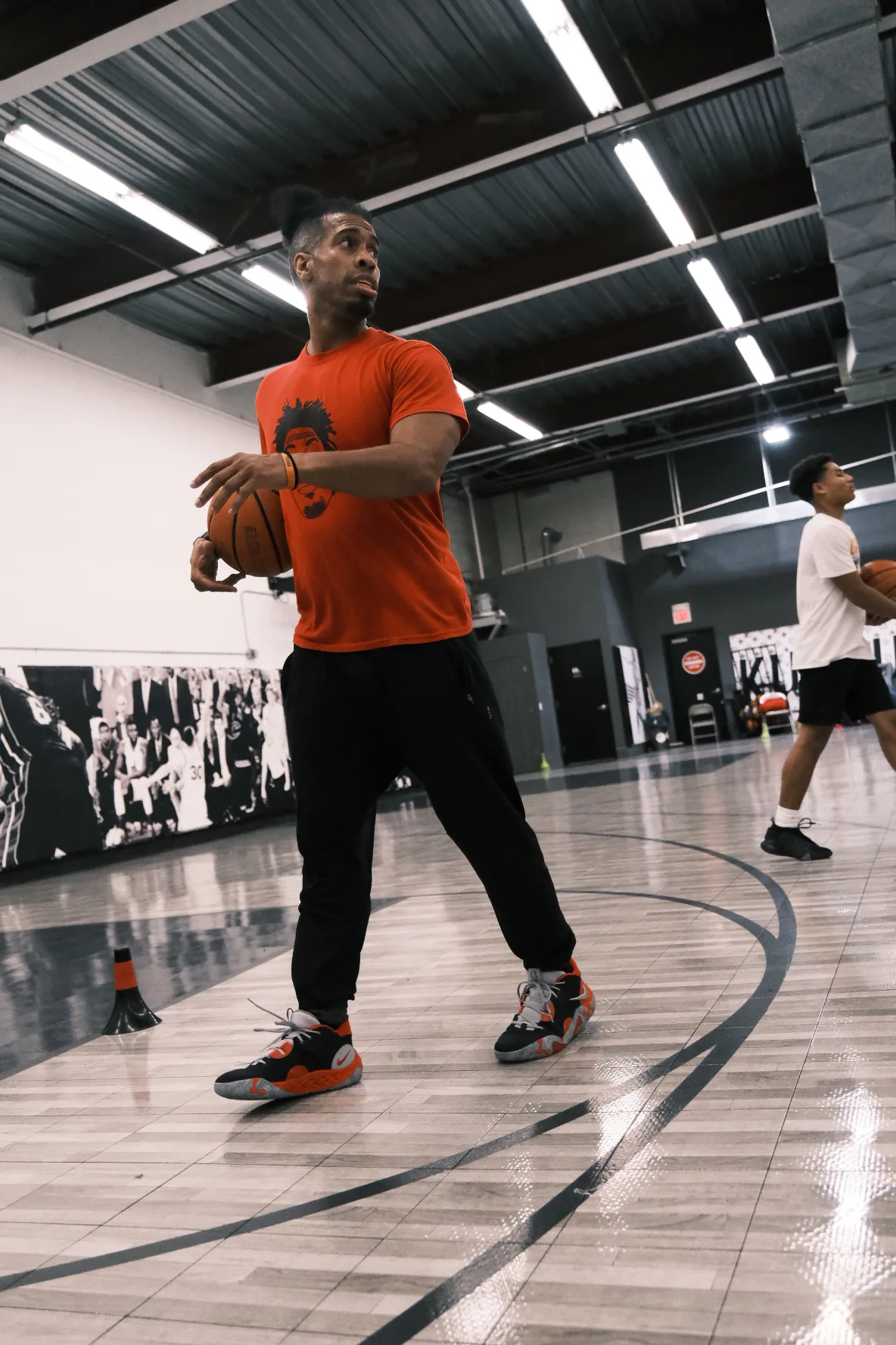 Ben Allen walking on court in orange training shirt with basketball